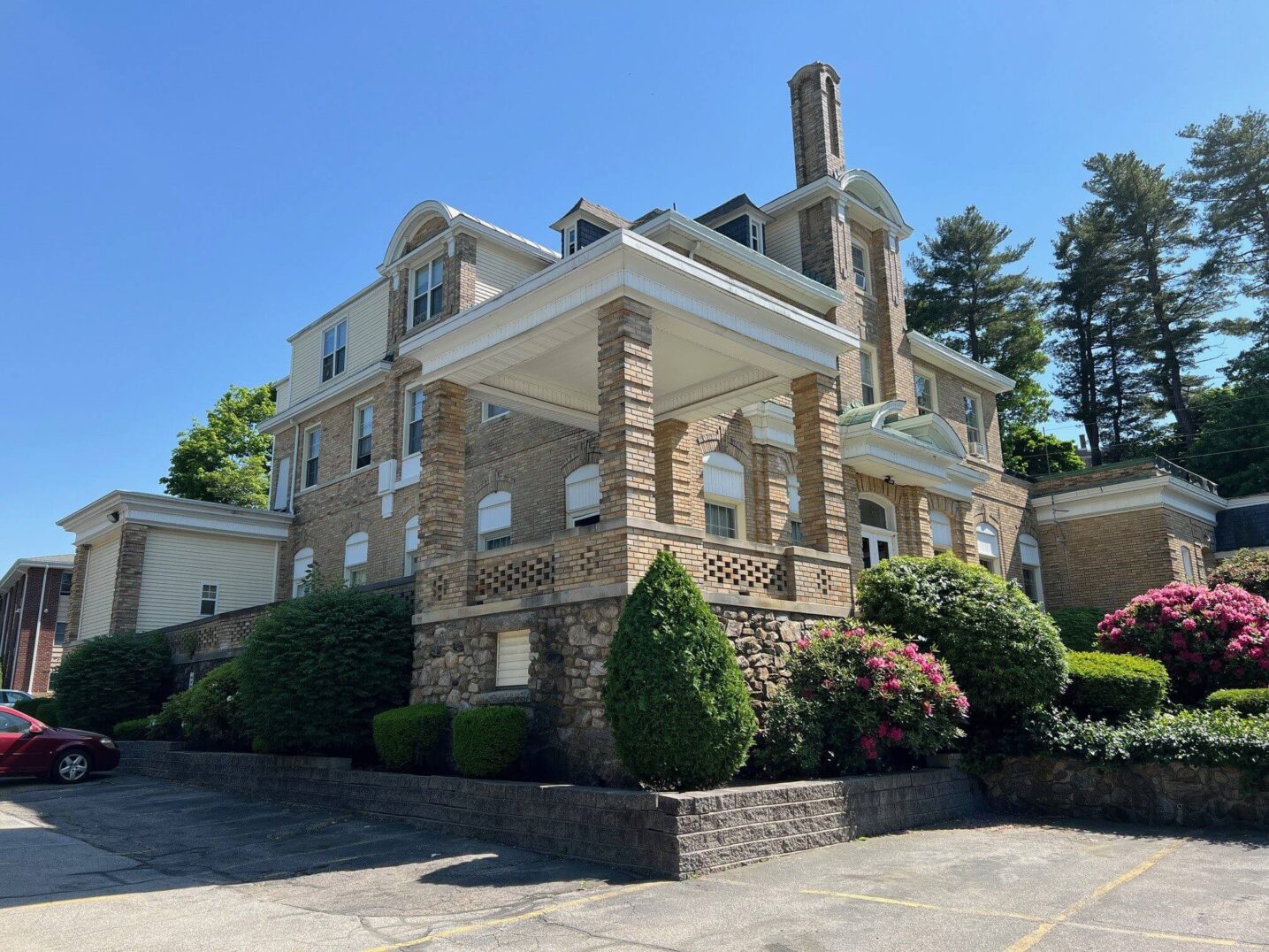 A large brick house with a prominent porch and manicured bushes.